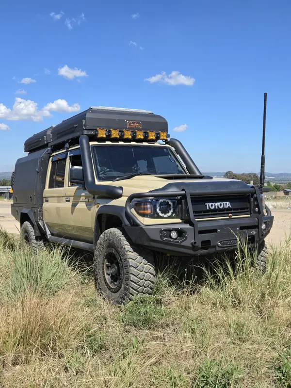 Tan Land Cruiser 79 with flatbed, canopy and light bar